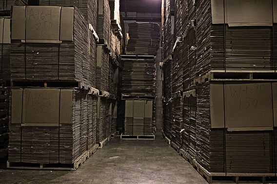 Old cardboard piled high on pellets in a warehouse. 